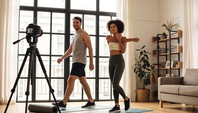 Couple recording home workout, stepping and stretching on mats in bright living room