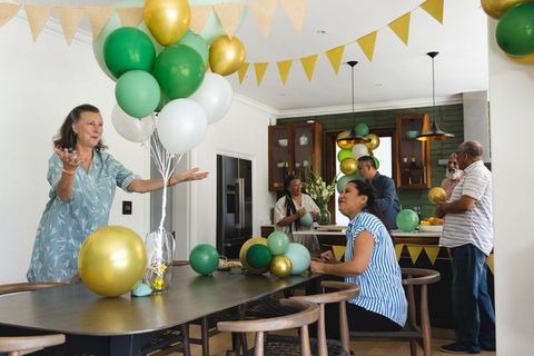 Multigenerational family decorating kitchen with green gold balloons for home celebration