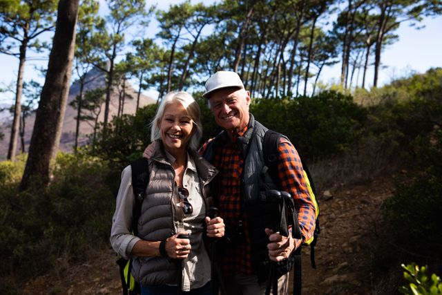 Front view of a happy senior Caucasian couple enjoying time in nature together, hiking in mountains, embracing, taking a break