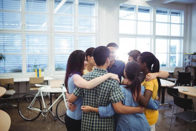 Group of happy business executives forming huddle in office