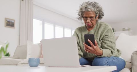 Senior Woman with Laptop and Smartphone in Relaxed Setting