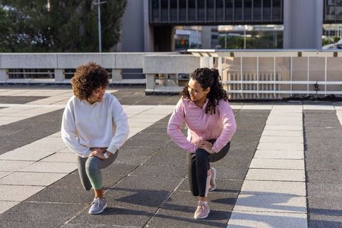 Urban rooftop fitness partners warming up with lunges during outdoor workout