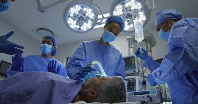 Biracial surgeons wearing protective clothing putting patient to sleep in operating theatre - Download Free Stock Photos Pikwizard.com