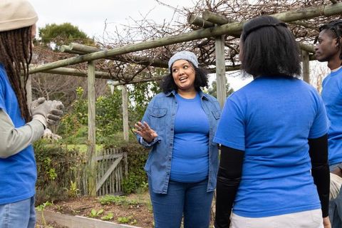 African american women leading community garden volunteer team under pergola