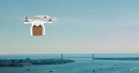Drone delivering package over coastal cityscape at sunset