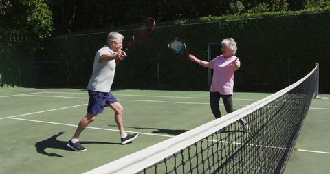 Senior Couple Celebrating After Tennis Match on Sunny Court