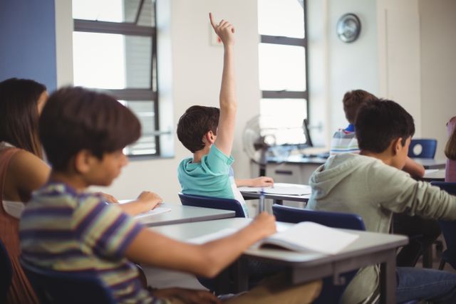 School kids raising hand in classroom at school