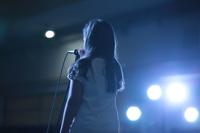 Young girl performing on stage under bright lights - Download Free Stock Photos Pikwizard.com
