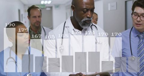 Medical team reviewing patient data on tablet with overlaid bar chart in hospital corridor
