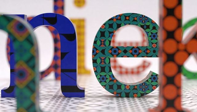 3d patterned lowercase letters forming vibrant geometric typography sculpture on tiled floor