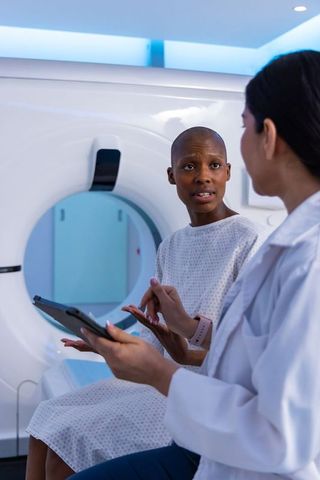 Diverse female patient consulting clinician at mri/ct scanner during radiology appointment