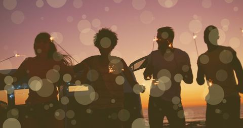 Silhouetted Friends Celebrating with Sparklers at Sunset Beach