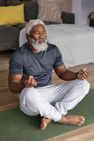 African american senior man meditating on yoga mat at home practicing mindfulness and calm