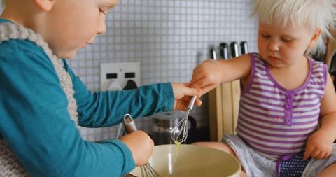 Caucasian Siblings Enthusiastically Mixing Eggs at Home