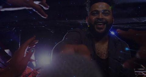 Energetic vocalist reaching into crowd smiling and grabbing mic under club spotlight