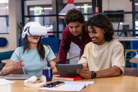 Young adults collaborating using vr headset and tablet in modern campus study space