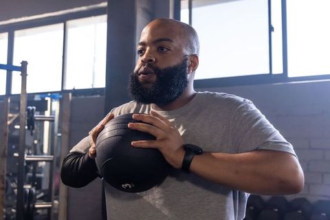 Performing medicine ball training in gym with backlit windows