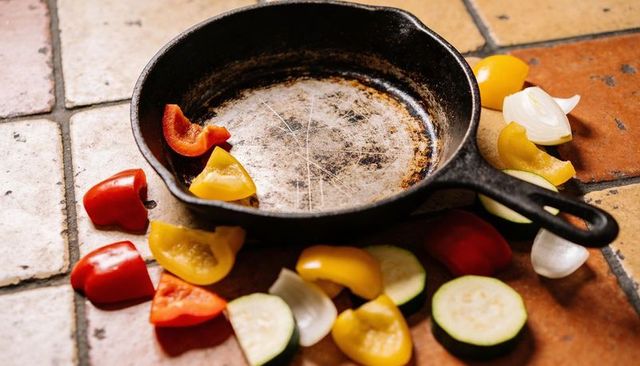Well-seasoned cast-iron skillet on rustic terracotta tiles with colorful vegetables