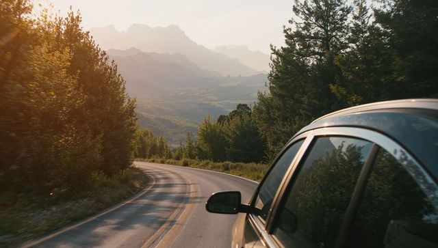 Sunlit car journey on captivating forest mountain road