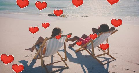 Romantic Couple Relaxing on Beach with Floating Hearts