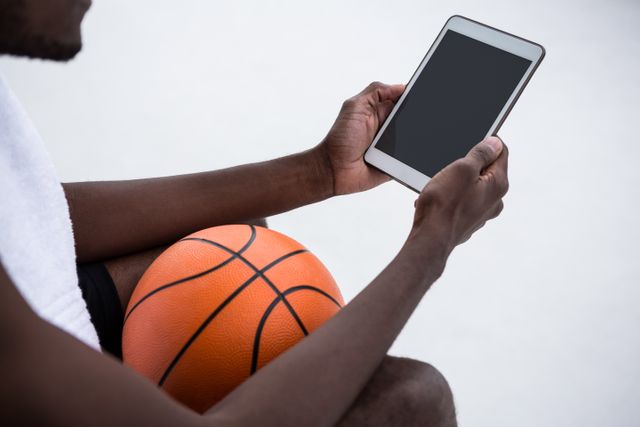 Player holding basketball while using digital tablet - Download Free Stock Photos Pikwizard.com
