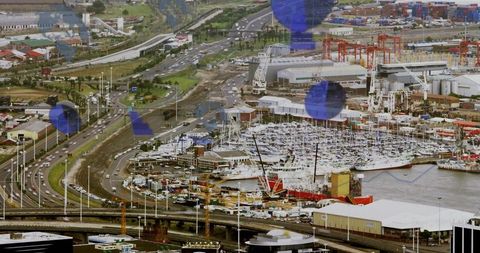 Coastal port marina showing moored yachts, workboats, gantry cranes and container yards
