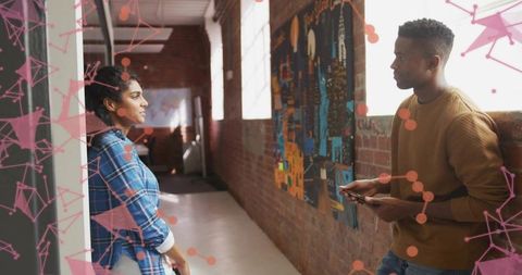 Leaning woman and man having conversation in industrial loft corridor with mural