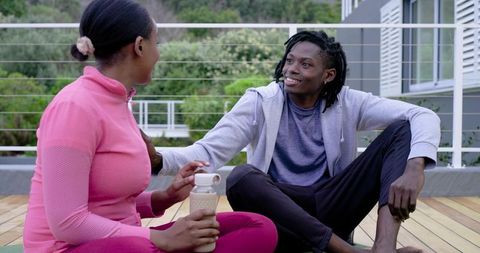 African American Couple Relaxing on Deck After Workout, Smiling and Talking Outdoors