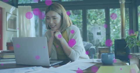 Woman Engaged in Video Call Amidst Playful Digital Dots at Home