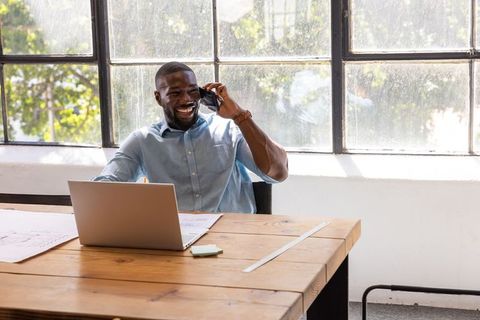 Smiling Professional Engaged in Phone Conversation at Modern Workspace