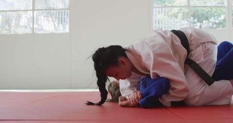 Two Female Judo Fighters Grappling in Bright Gym