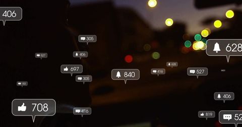 Hooded driver glancing at social alerts while driving at night with neon bokeh urban backlight