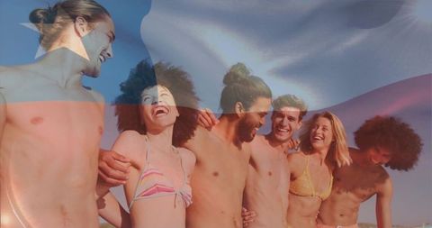 Laughing friends embracing on sunlit beach with national flag overlay celebrating summer