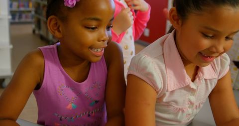 Diverse Schoolgirls Collaborating on Laptop in Library