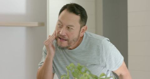 Senior Man Performing Skincare Routine in Modern Bathroom