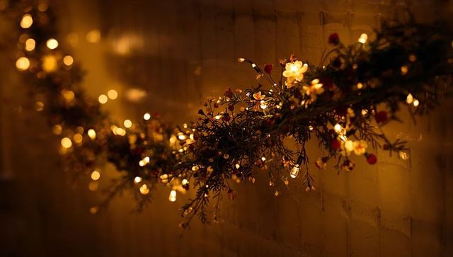 Warm Garland with Fairy Lights and White Flowers on Brick Wall Creating Cozy Glow