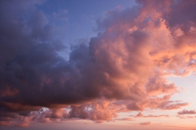 Dramatic cloudscape with vibrant hues of orange and purple during sunset. Ideal for use in nature-related content, website backgrounds, or atmospheric art projects. Perfect for conveying tranquility, beauty, and the majesty of natural phenomena.