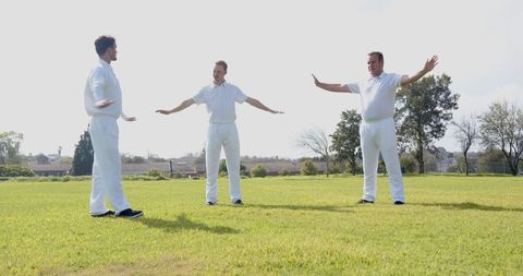 Male cricket teammates stretching on field for warm-up