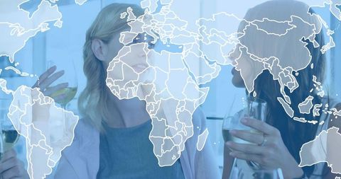 Women clinking wine glasses and chatting with translucent world map overlay