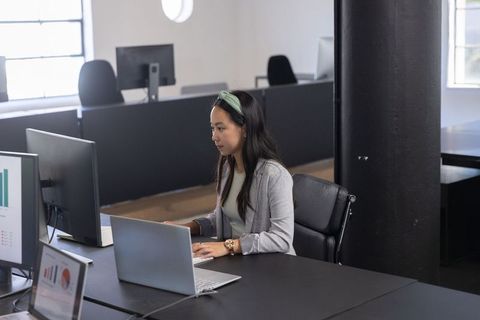 Focused Asian Woman Working on Laptop in Modern Open-Plan Office