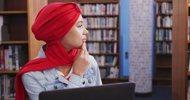 Thoughtful Muslim Woman in Red Hijab Working on Laptop in Library - Download Free Stock Images Pikwizard.com