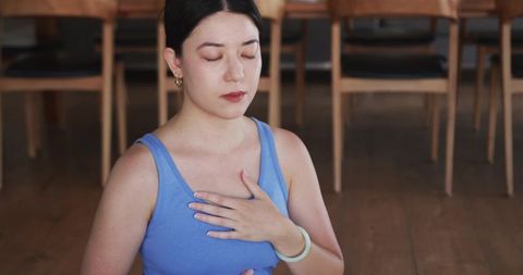 Asian woman practicing mindful breathing and chest-centered meditation sitting in studio