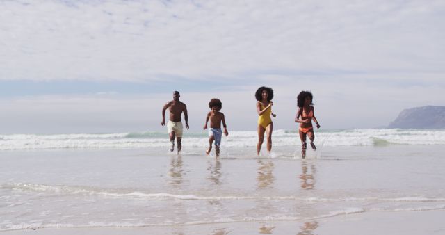 African american parents and two children running at the beach. family outdoor leisure time by the sea.