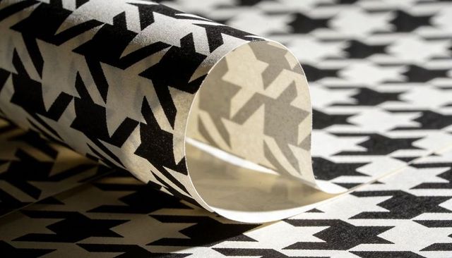 Curled monochrome geometric wallpaper featuring bold houndstooth-like graphic pattern