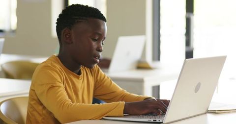 Focused Young African American Student Typing on Laptop in Bright Modern Classroom