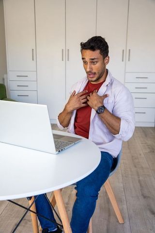 Man Expressing Emotion While Using Laptop in Modern Living Room