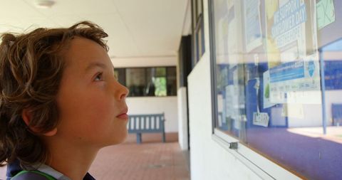 Elementary student observing notice board in school corridor
