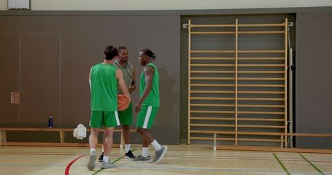 Coach directing team huddle on indoor basketball court during focused practice session