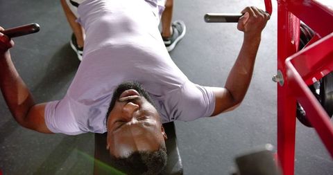 Man focused on weightlifting exercising on gym bench