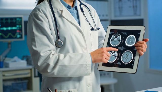 Doctor holding tablet and pointing at brain mri scans with stethoscope for neurology consultation
